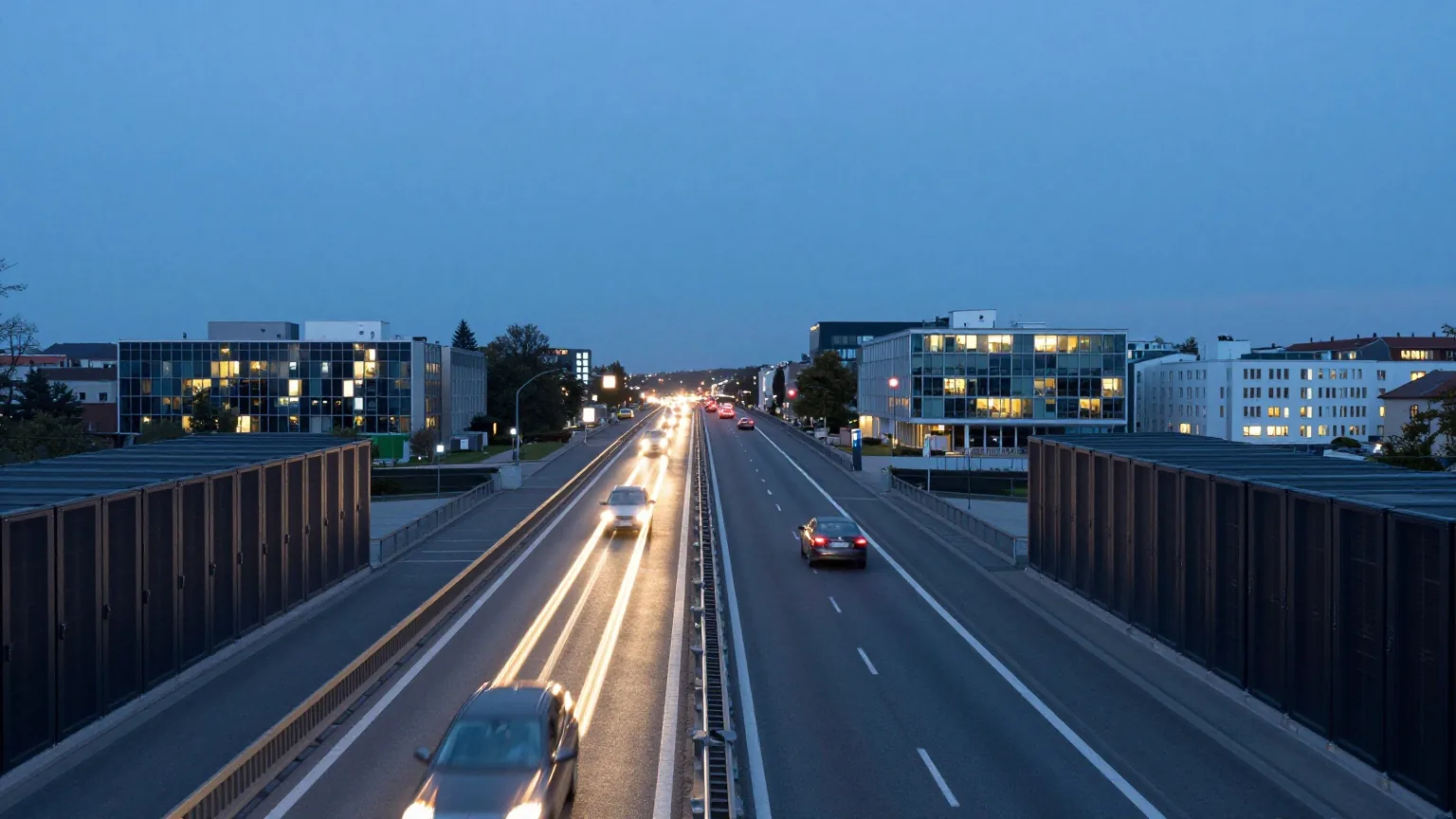 Lange Schnellstraße in der Dämmerung mit Lichtspuren fahrender Autos vor einer fernen Stadt