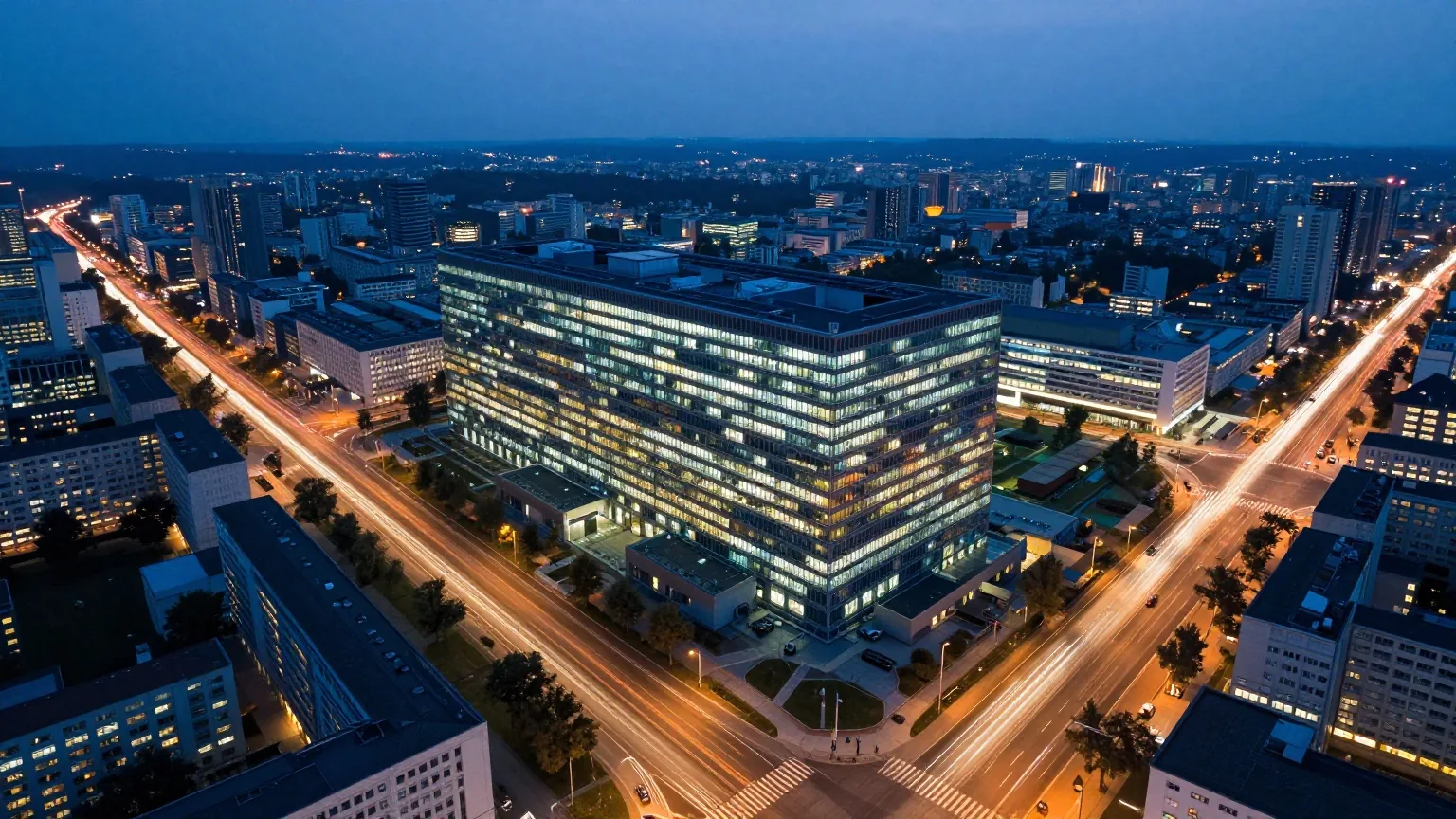 Stadt in der Dämmerung von oben, Lichtspuren auf Straßen führen zu einem beleuchteten Rechenzentrum